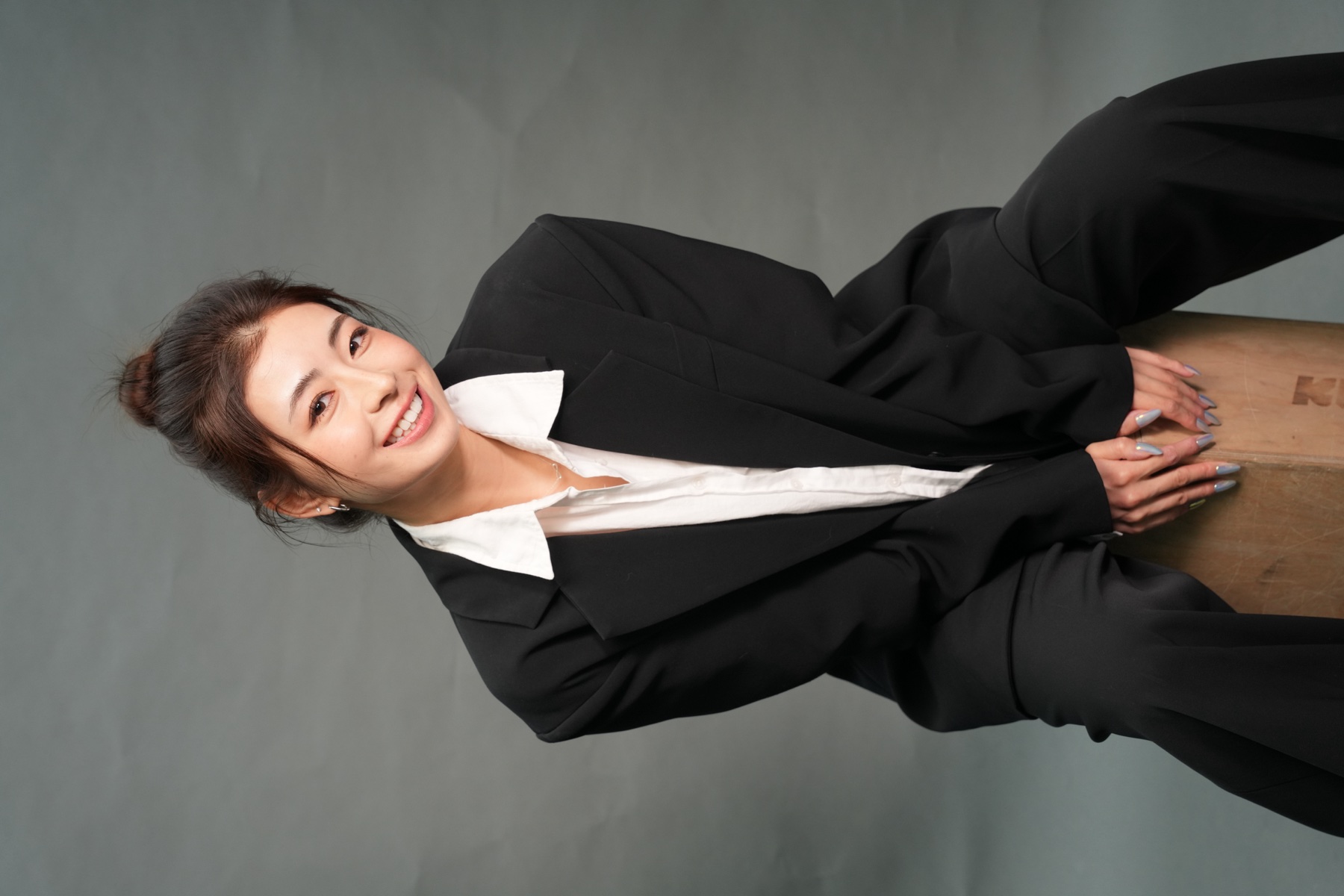 Amy Wang, seated portrait in a black suit